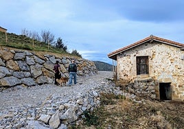 Una pareja pasea por el camino ahora paralizado junto a una cabaña semienterrada por el vial.