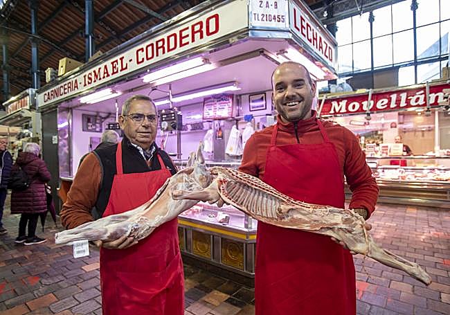 Ismael Gil, padre e hijo, con los lechazos frente a su puesto en el Mercado de La Esperanza.