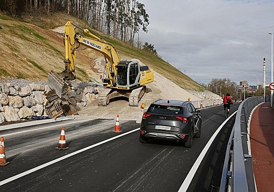 Vehículos circulan por el tramo afectado por el deslizamiento, donde trabaja una excavadora, en la carretera Viveda-Duález.