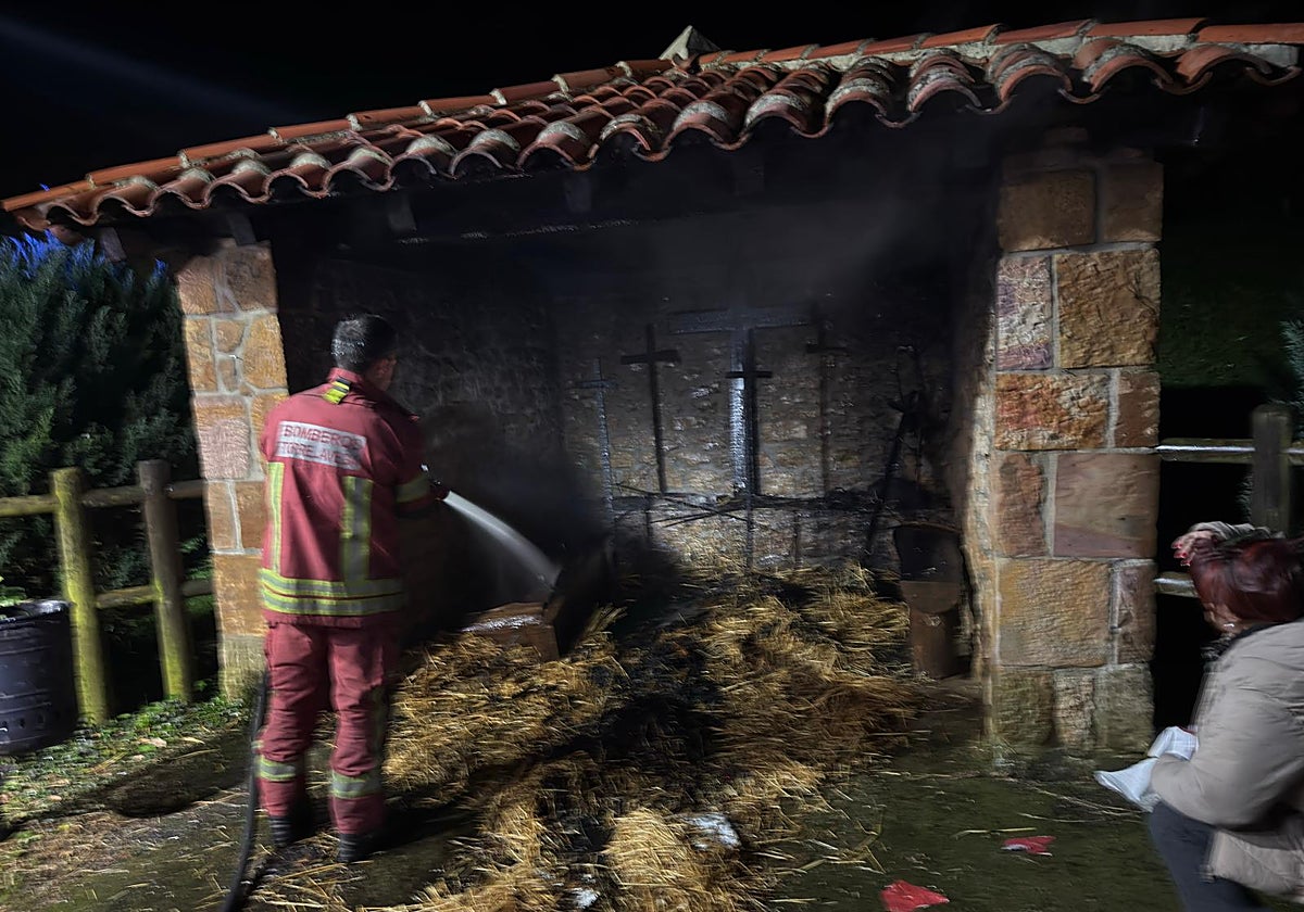 Un bombero sofoca el incendio en el Belén de Oreña.