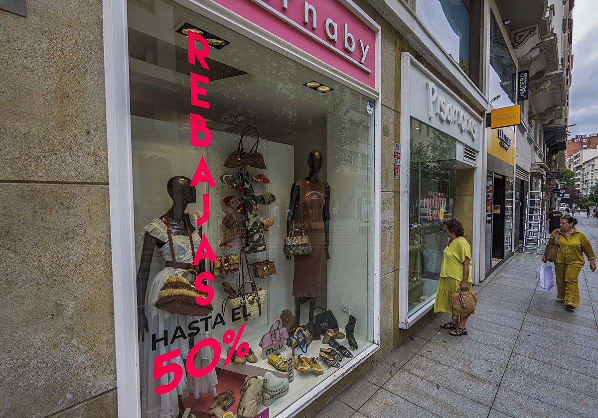 Dos mujeres atraviesan la calle Juan de Herrera de Santander con varios comercios en rebajas.