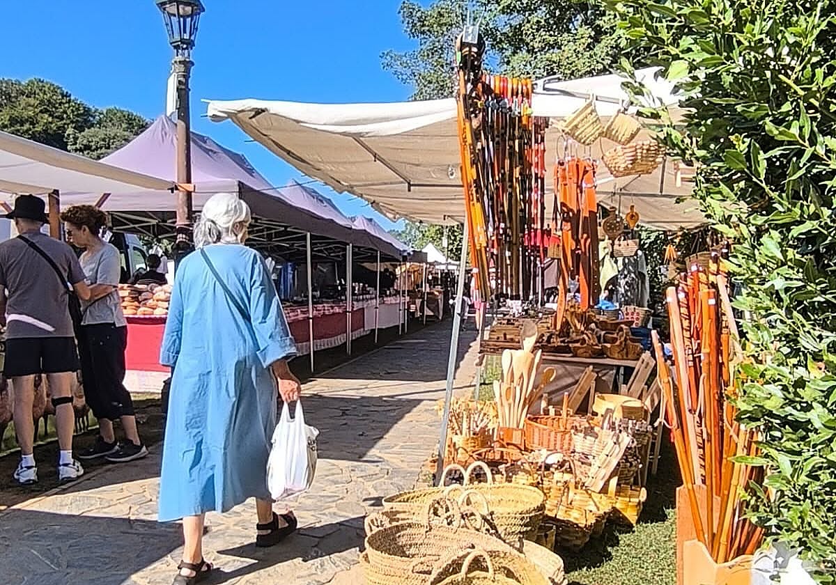 Una mujer pasea por el mercado de productos regionales y artesanales de otros años.