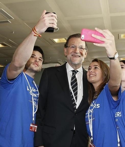Rajoy se fotografía junto a dos jóvenes. 