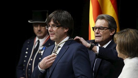 Artur Mas impone la medalla representativa del cargo al nuevo presidente de la Generalitat, Carles Puigdemont.