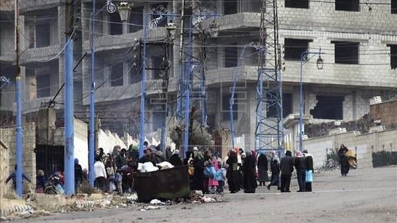 Varias personas esperan a las afueras de la localidad siria de Deir al Zur. 