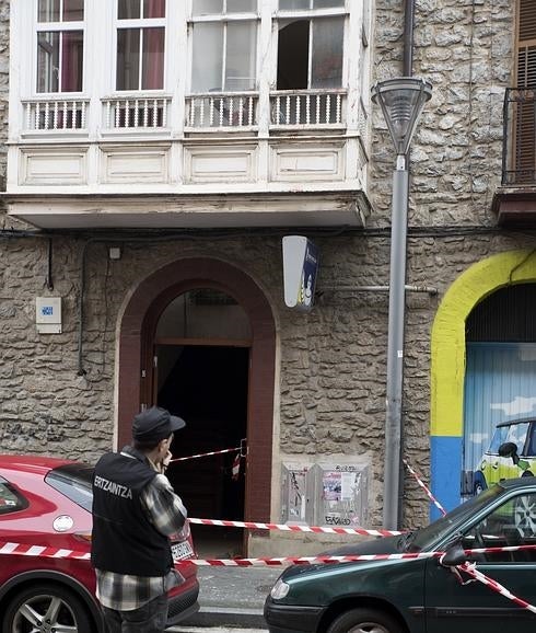 Un ertzaina toma fotografías en la entrada del domicilio donde se produjeron los hechos. 