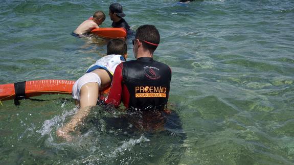 Un voluntario ayuda a un niño a meterse en el agua.