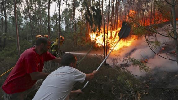 Varios vecinos intentan sofocar las llamas del incendio forestal de Arbo (Pontevedra).