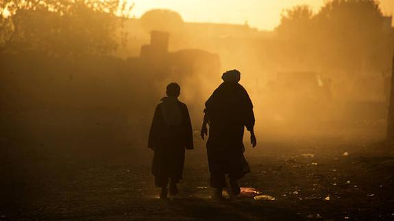 Dos personas caminan por una carretera de herat (Afganistán).