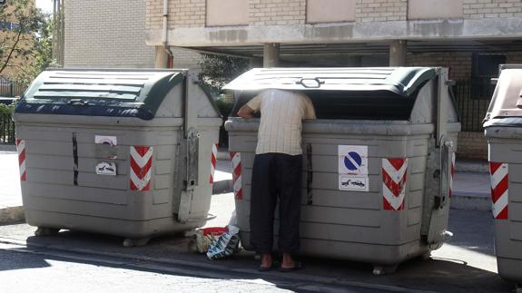 Una persona busca comida en la basura