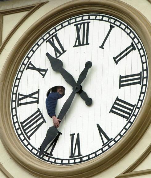 Un operario cambiando la hora de un reloj.