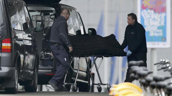 Dos personas retiran uno de los cádaveres del atentado de Bruselas.