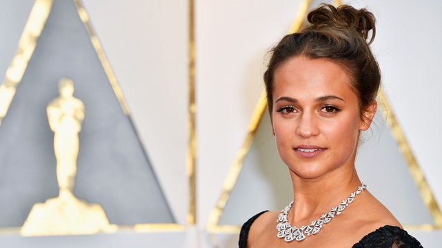 Alicia Vikander con moño alto y maquillaje natural en los Oscars 2017.