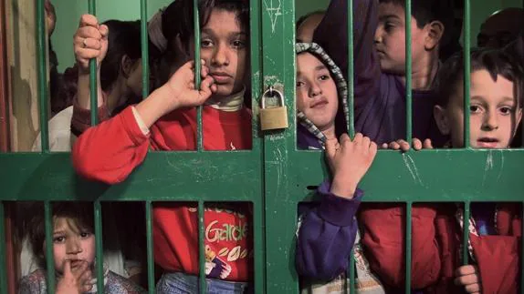 Niños albano kosovares, trasladados a Italia, aguardan la comida tras la verja de una escuela de Lecce.  