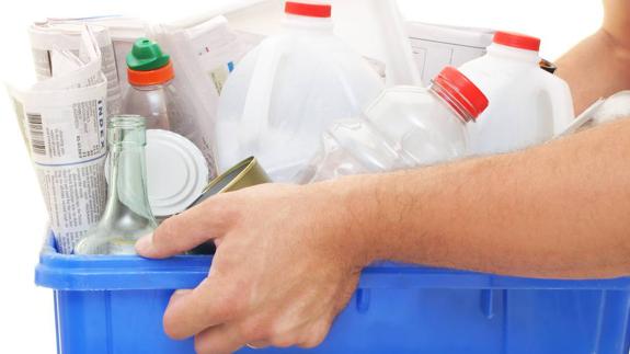 Una mujer traslada un recipiente lleno de material para reciclado. 