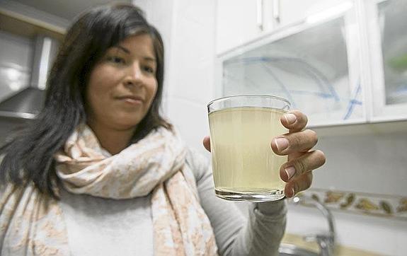 Verónica Montiel sostiene un vaso de agua amarillenta en la cocina de su vivienda, en el barrio La Rañada.