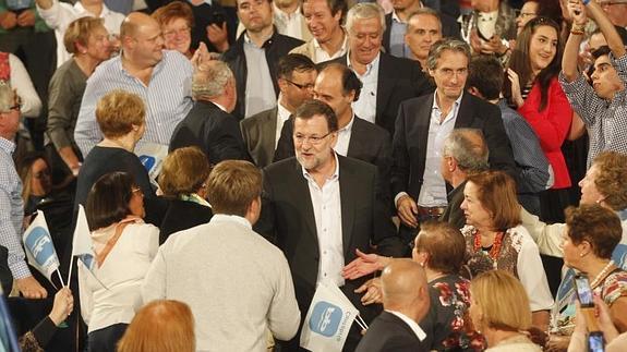 El público, que ha llenado el Palacio de Festivales, saluda a Rajoy.