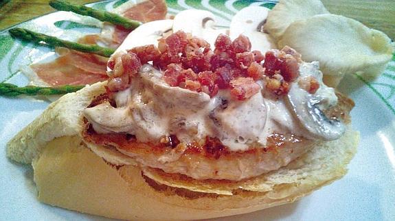 Solomillo de cerdo con guarnición dde setas, virutas de jamón y salsa de queso sobre tosta de pan.
