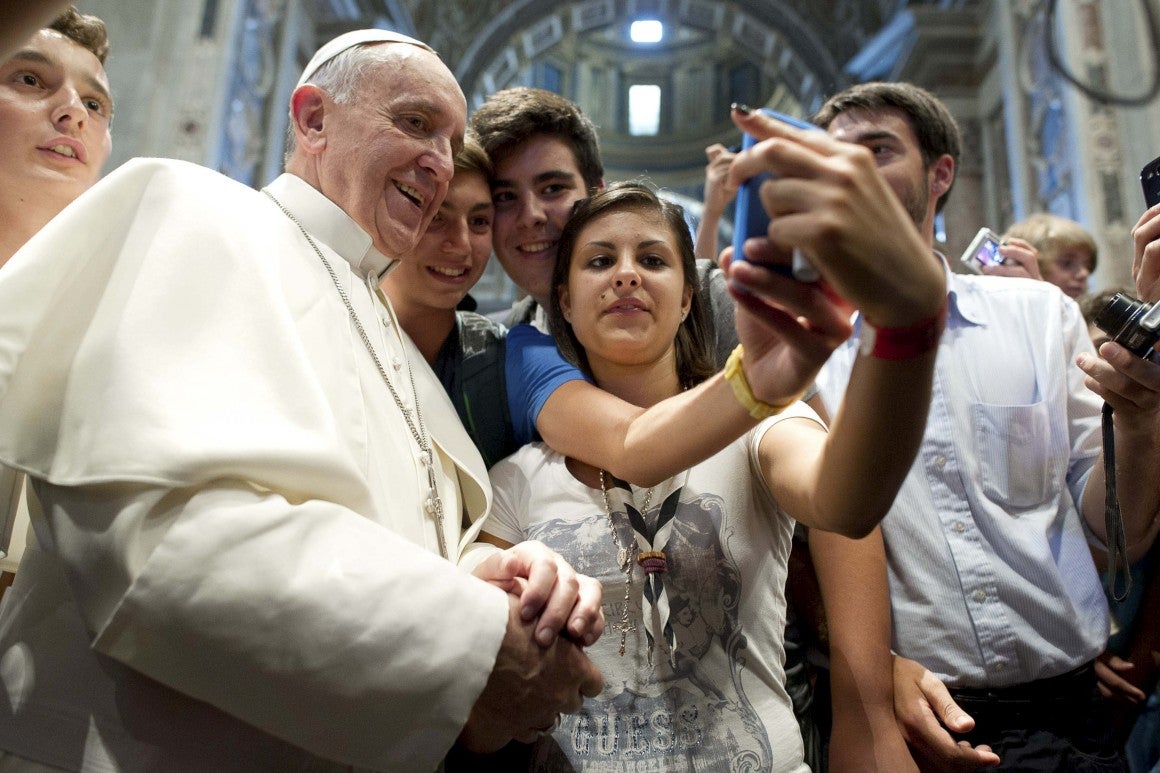 Francisco sonríe mientras unos jóvenes se sacan con él una fotografía con el móvil.