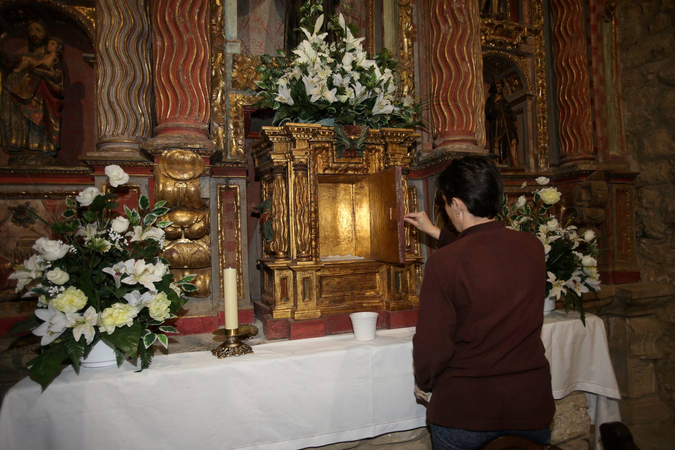Una mujer observa el sagrario vacío en la iglesia de San Román, en Puente Viesgo