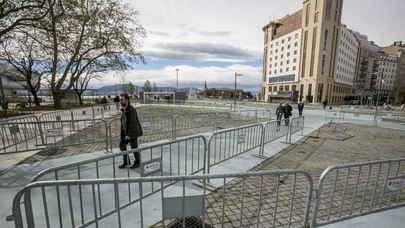 Una pareja camina entre las vallas que tiró el viento por la mañana en la Plaza de Alfonso XIII. 