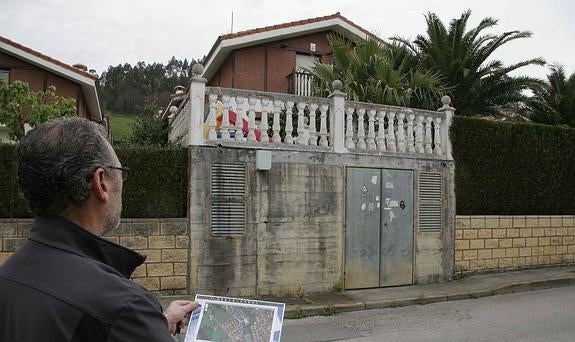 Adolfo muestra un plano de su urbanización frente a la vivienda que no puede vender por falta de licencia.