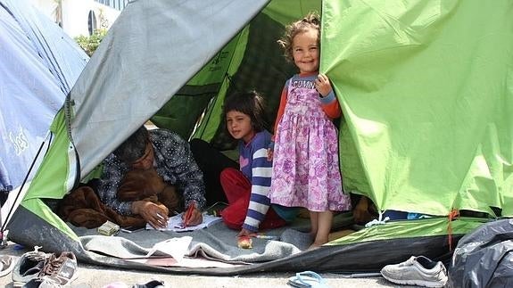 Unos niños sirios con su padre en la tienda de campaña en la que viven desde hace dos meses.