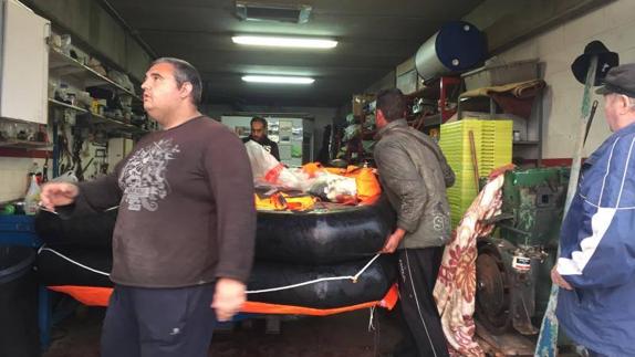 Tres de los marineros meten su balsa en una bodega del puerto de Santander, sobre las 7.30 horas, después de que compañeros de otro barco los rescataran.