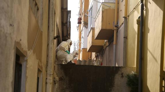 Operarios con trajes especiales proceden a la retirada de tejados de uralita entre los talleres y las viviendas colindantes.