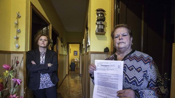 María Cruz Núñez, a la derecha, muestra junto a su hija la notificación enviada por el Ayuntamiento para que deje en un mes su hogar de más de 30 años.