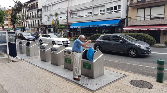 Un hombre deposita una bolsa de basura en San Vicente de la Barquera.