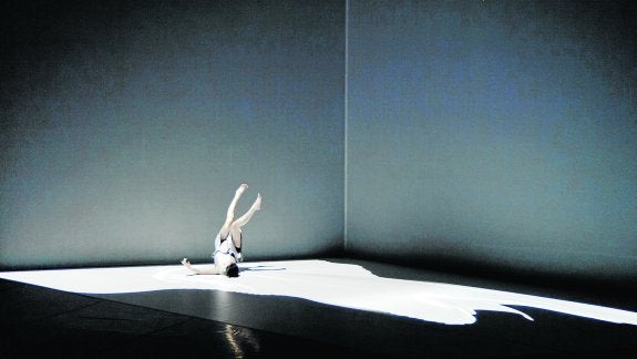 Tres bailarines sobre el escenario se mueven entre imágenes geométricas realizadas con nuevas tecnologías. 