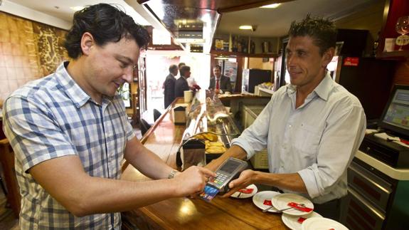 Un cliente paga con una tarjeta de crédito en un establecimiento hostelero de Santander