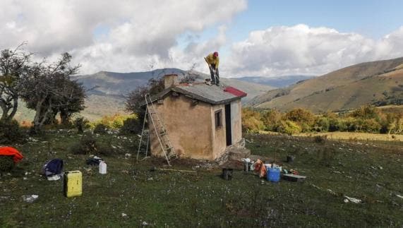 Un operario contratado por el Ayuntamiento trata el techo de la cabaña de Izara.