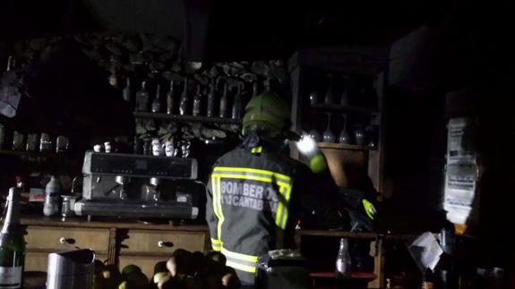 Un bombero inspecciona la barra del restaurante de San Mamés de Meruelo donde se produjo uno de los incendios.