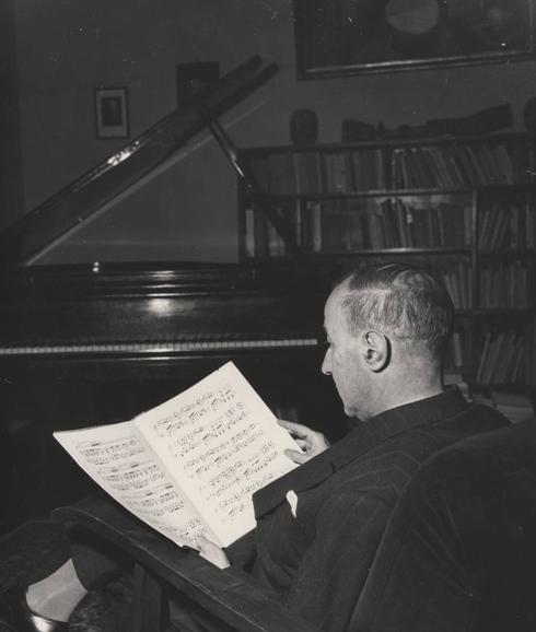 El poeta Gerardo Diego examina una partitura ante su piano