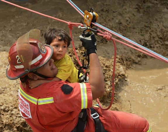 Salvamento. Un bombero rescata a un niño en la localidad de Huachipa, al este de Lima.