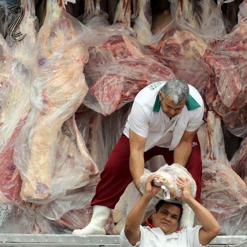 Carne en mal estado. Dos trabajadores se pasan una pieza de carne mientras descargan un camión en Sao Paulo.