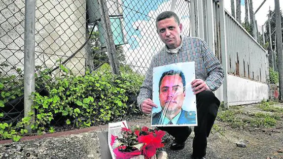 Javier Pernía posa con un retrato de Juan Manuel Piñuel en el exterior de las ruinas del cuartel de la Guardia Civil de Legutiano
