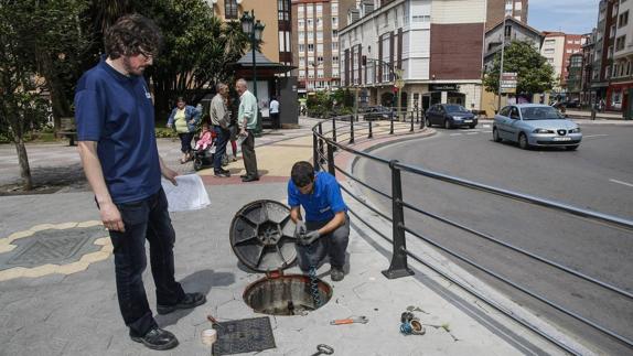 Operarios de la empresa Aguas Torrelavega trabajan en la red de abastecimiento en la Plaza Tres de Noviembre. 