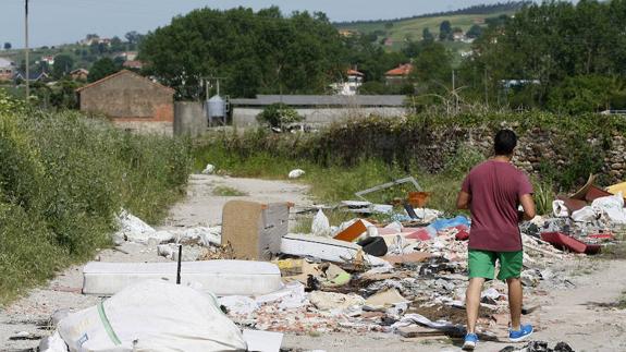 Un vecino camina junto a uno de los vertederos incontrolados donde frecuentemente se acumula basura en la zona de Tanos-Viérnoles.