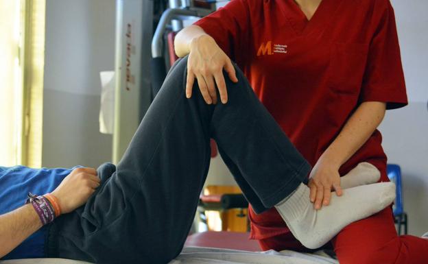 Atención de una fisioterapeuta a uno de los afectados por la esclerosis múltiple. 