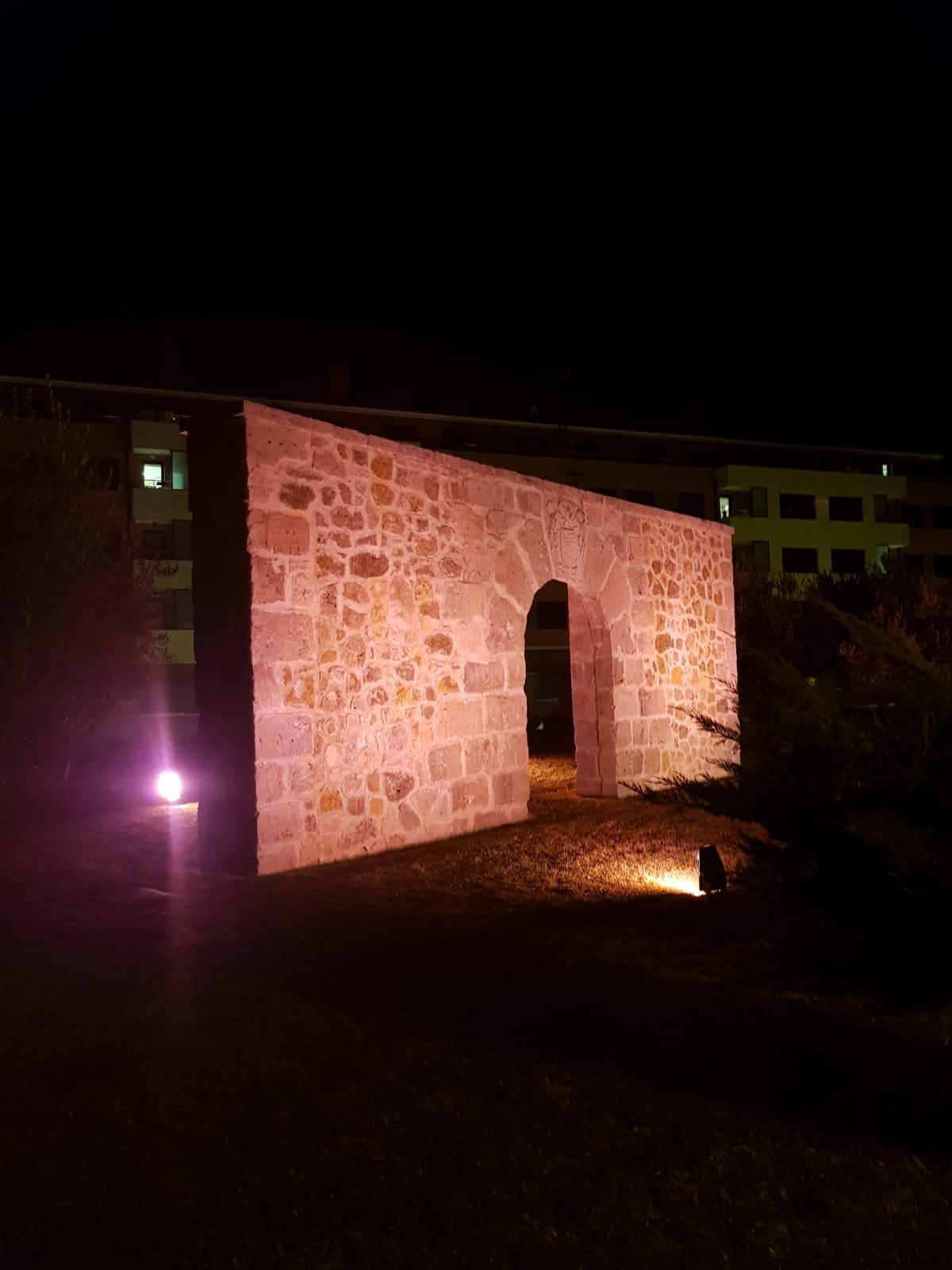 Pórtico de entrada a la iglesia de Arroyo iluminada en rosa. 
