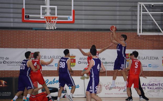 Ángel Pérez lanza a canasta en suspensión ante la mirada de sus compañeros y la defensa del CB La Flecha. 