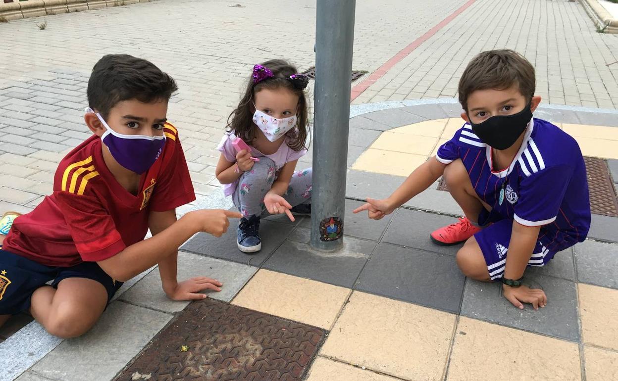 Tres niños de Arroyo señalan un gnomo localizado en la base de una farola junto a un parque infantil del municipio. 