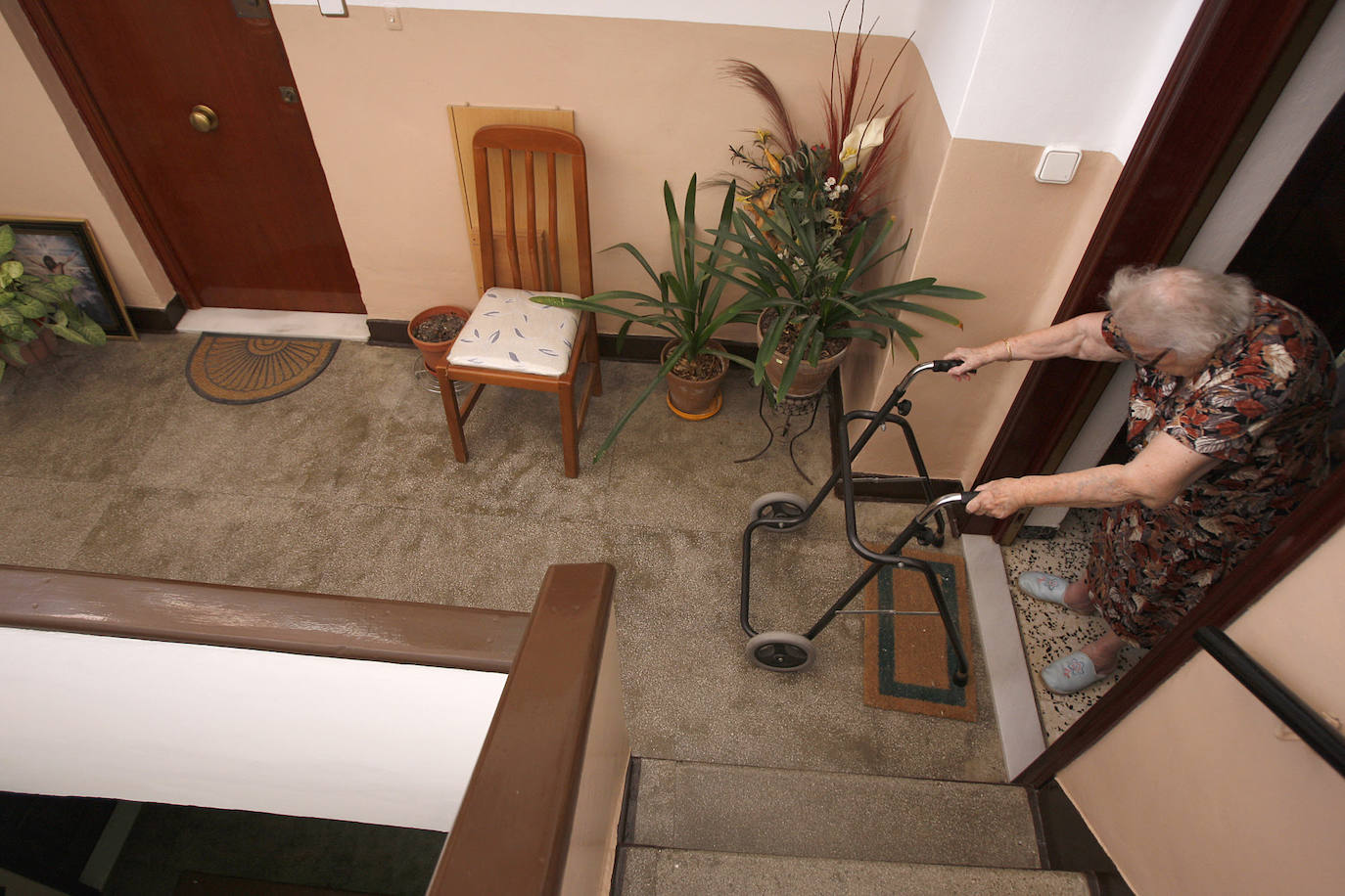 Una mujer con su andador en la entrada a su domicilio