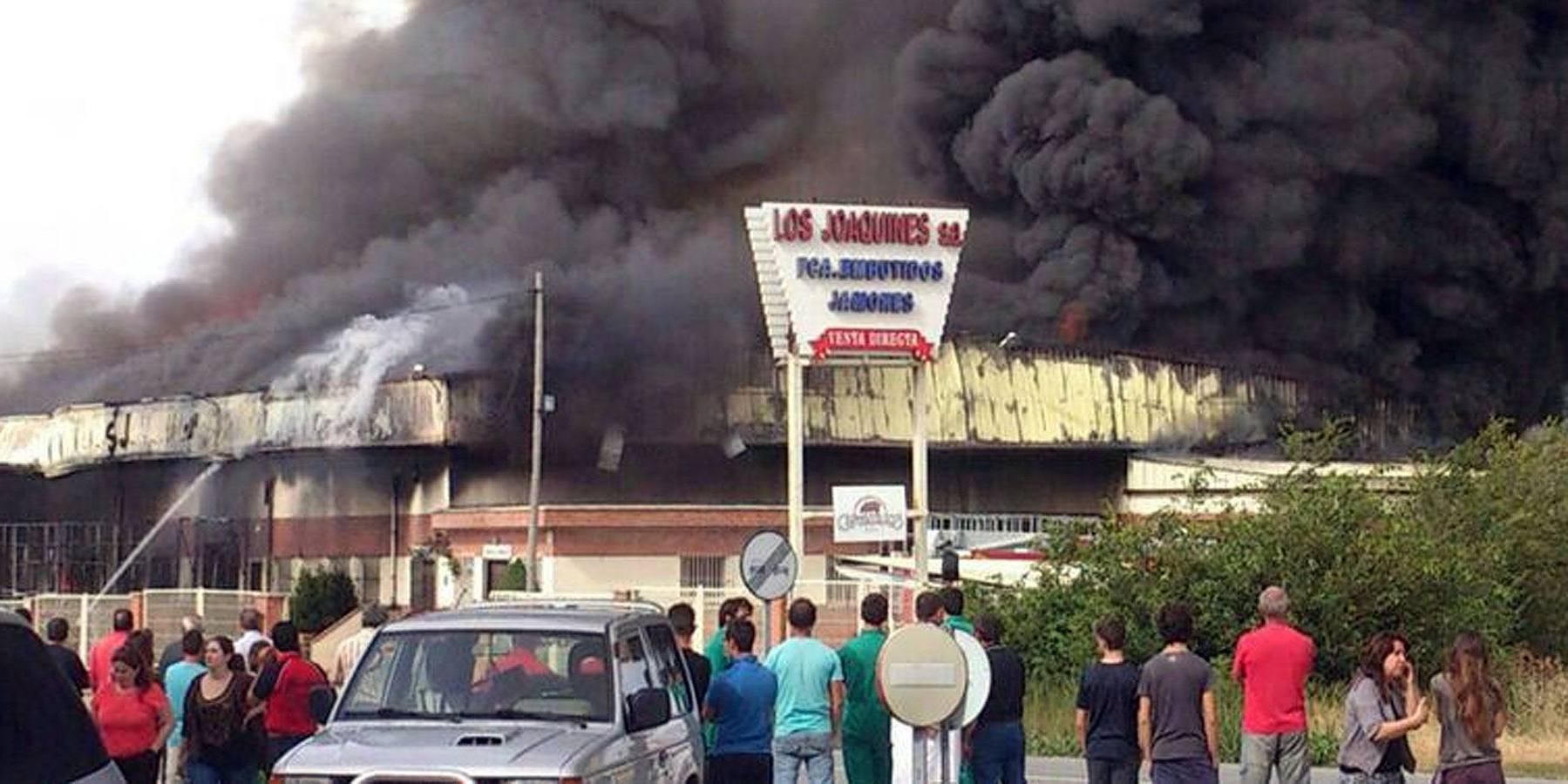 04.07.14 Testigos del incendio observan la densa humareda que envuelve la fábrica jamonera Los Joaquines de Pinillos de Polendos, Segovia.