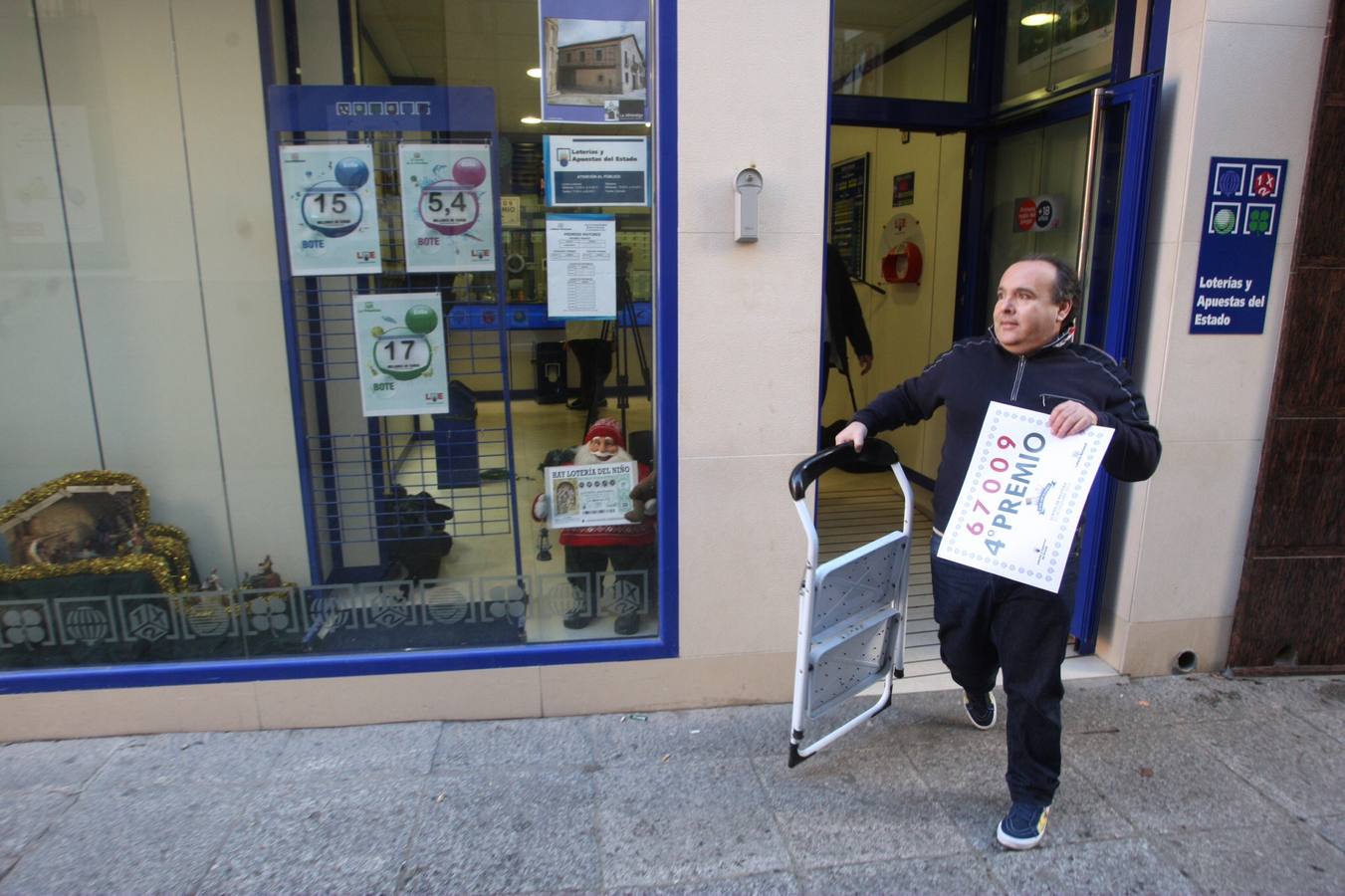 Ávila. El propietario de la administración número 3 de Arévalo, Fernando Muriel, se dispone a colgar el cartel que acredita la venta del cuarto premio de la Loteria de Navidad.