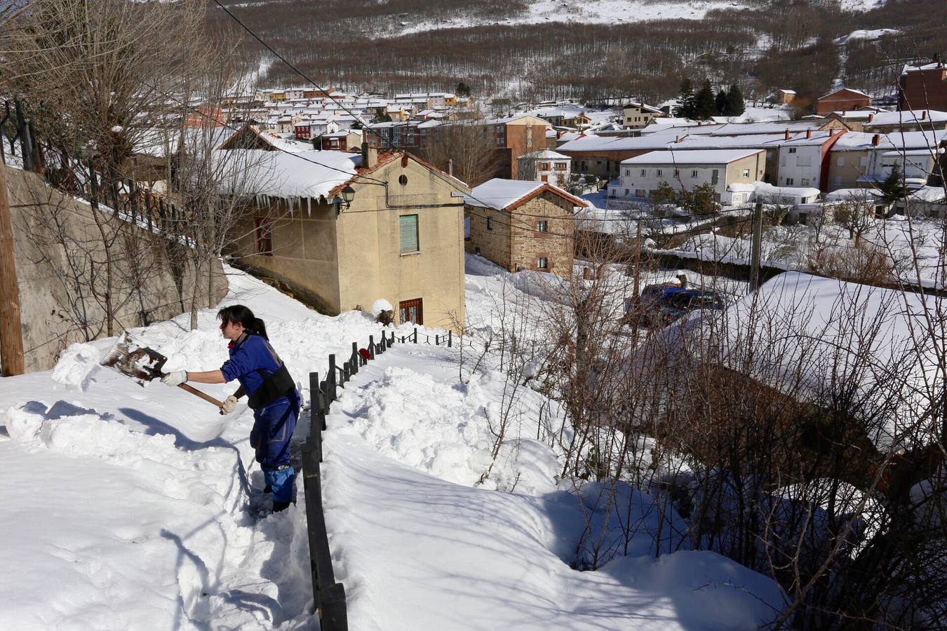 Blanca del ayuntamiento de Barruelo limpia de nieve una escalera de acceso a viviendas.