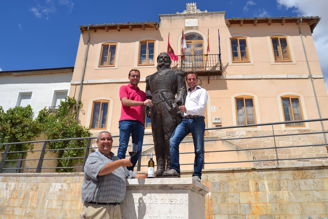 26.08.14 Los hermanos David Rodriguez y Carlos Rodríguez (arriba) y César Salvador, de la Bodega Malacuera, junto a la estatua del Empecinado, en la plaza de Castrillo de Duero (Valladolid).
